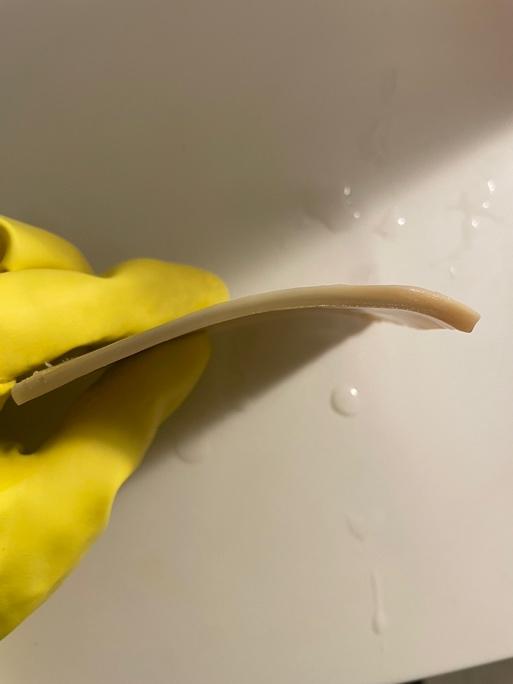 A hand in a yellow glove holding a piece of horn